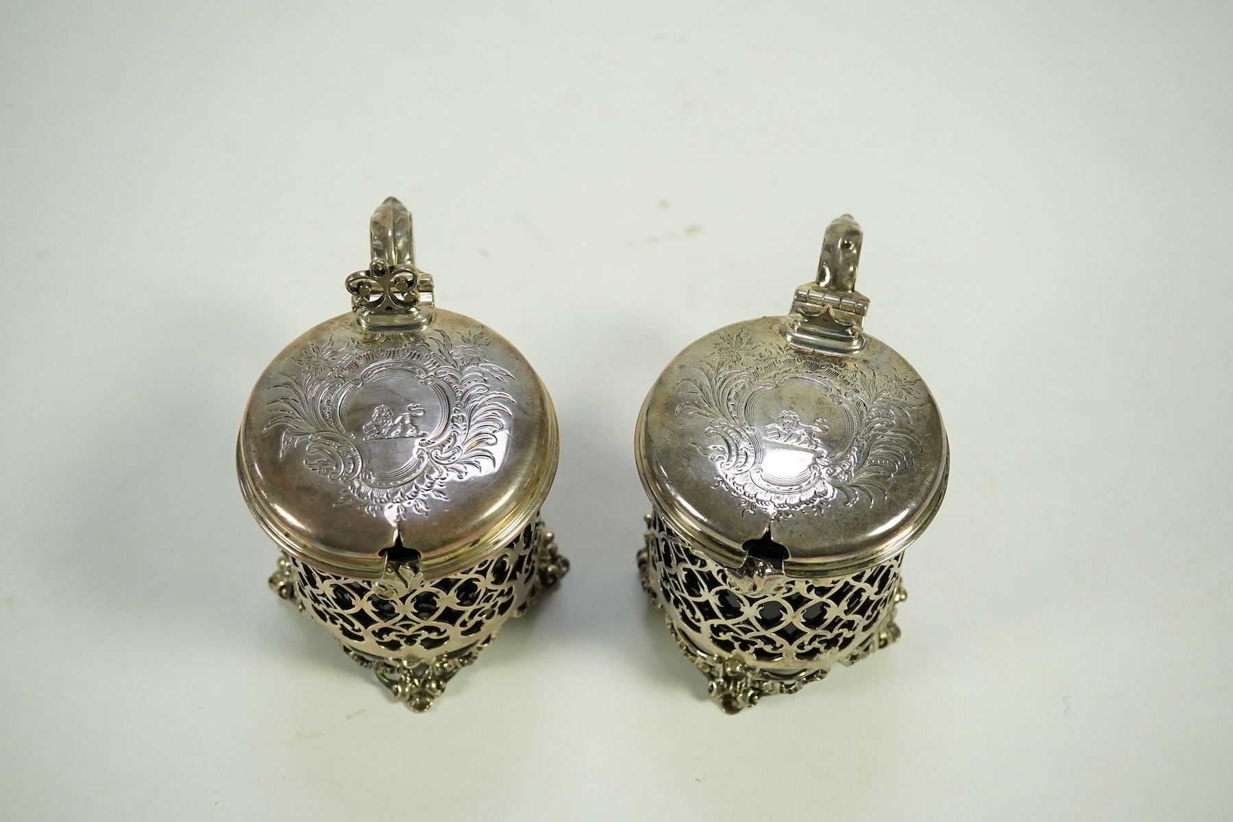 A near pair of ornate Victorian pierced silver drum shaped mustard pots and covers, one by Charles Thomas Fox & George Fox, the other by George Fox